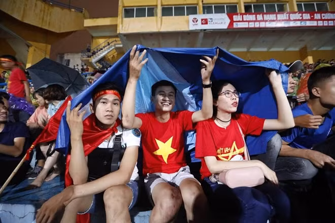 Cổ động viên đội mưa cổ vũ cho Olympic Việt Nam. (Ảnh Phong Sơn)