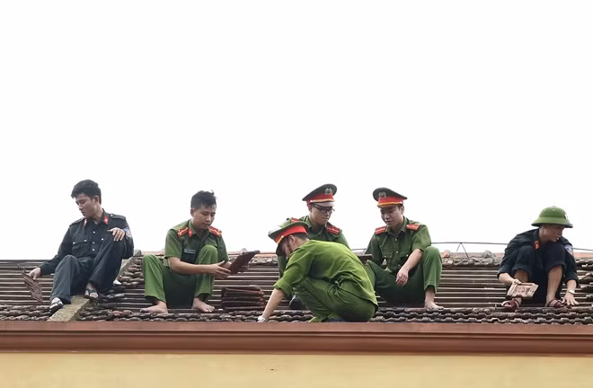 Lực lượng công an, quân đội lợp lại mái trường học tại xã Kỳ Nam, huyện Kỳ Anh. - Ảnh: VGP/Quang Hiếu