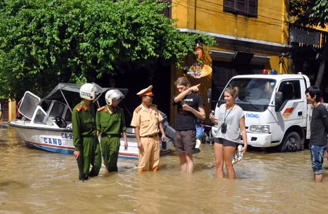 Công an TP Hội An, tỉnh Quảng Nam, dầm mình trong nước lũ hướng dẫn du khách nước ngoài không được đến các khu vực ngập lụt sâu trong phố cổ. Ảnh: Văn Long (Đà Nẵng).