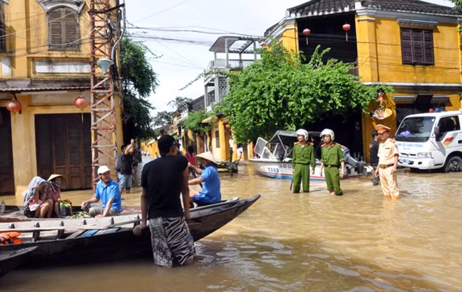 Công an TP Hội An, tỉnh Quảng Nam, dầm mình trong nước lũ hướng dẫn du khách nước ngoài không được đến các khu vực ngập lụt sâu trong phố cổ. Ảnh: Văn Long (Đà Nẵng).
