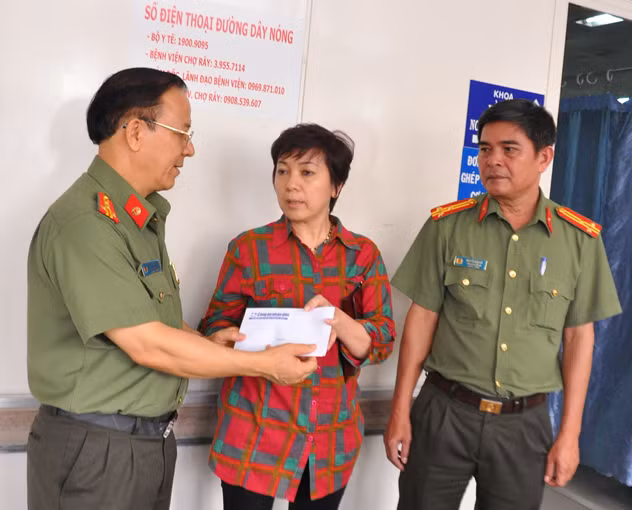 Đại tá Nguyễn Thanh Hải gửi tiền hỗ trợ của báo CAND tới người thân của anh Lê Quang Vũ tại BV Chợ Rẫy.