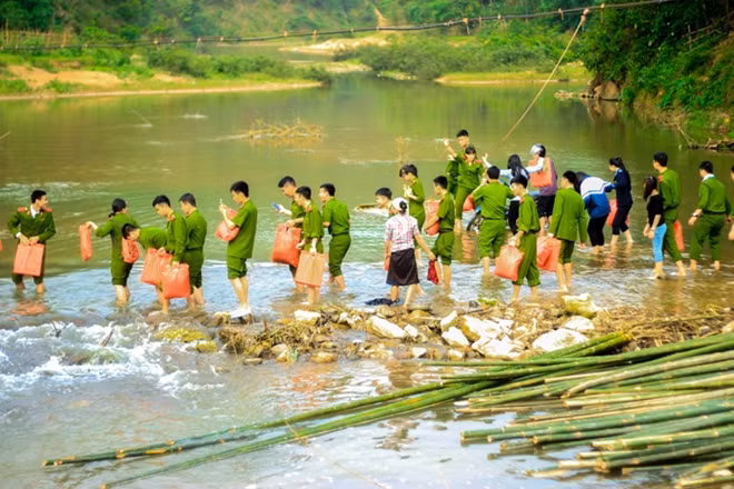 Tình nguyện viên CLB tình nguyện Học viện Cảnh sát nhân dân lội suối mang quà từ thiện lên các bản vùng cao trong chương trình thiện nguyện tại xã Tam Văn, huyện Lang Chánh, tình Thanh Hóa : Tác giả: Lê Hồng Nam (Học viện CSND).