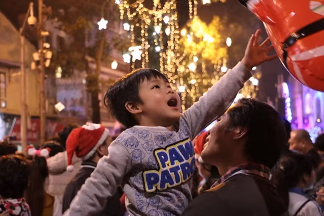 Một em bé được bố mẹ cho đi chơi đêm Giáng sinh.