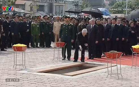 Tổng bí thư Nguyễn Phú Trọng dẫn đầu đoàn lãnh đạo cấp cao thả nắm đất và những cánh hoa cúc đầu tiên xuống huyệt mộ.