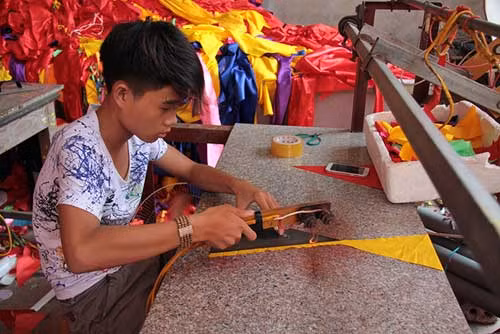 Mỗi người thực hiện một công đoạn khác nhau. Một công nhân đang thực hiện công đoạn cắt cánh ngôi sao.