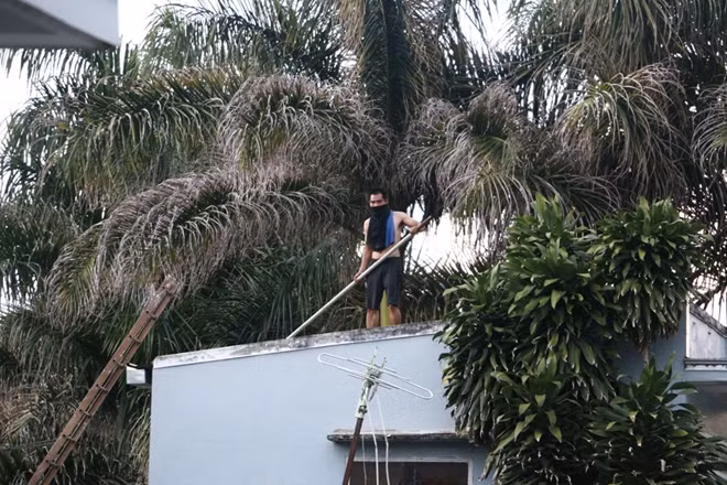 Nam thanh niên có biểu hiện ngáo đá cầm gậy nhảy múa trên nóc nhà.