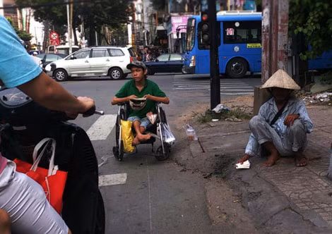 Tại giao lộ Trần Hưng Đạo- Châu Văn Liêm (quận 5) lúc 9h sáng, một thanh niên ngồi trên xe lăn với đôi chân bị tật ngả nón xin tiền người đi đường, bên cạnh là một người lớn tuổi bán vé số.