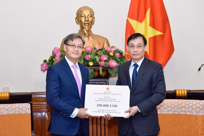 Đồng chí Lê Hoài Trung, Thứ trưởng Bộ Ngoại giao trao cho Đại sứ Thongsavanh Phomvihane 200.000 USD của Chính phủ Việt Nam.