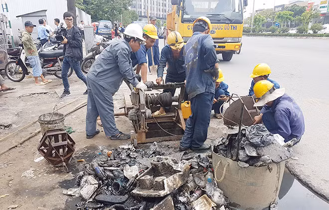 Công nhân thoát nước đô thị vớt rác từ một miệng cống thoát nước. Công nhân thoát nước đô thị vớt rác từ một miệng cống thoát nước.