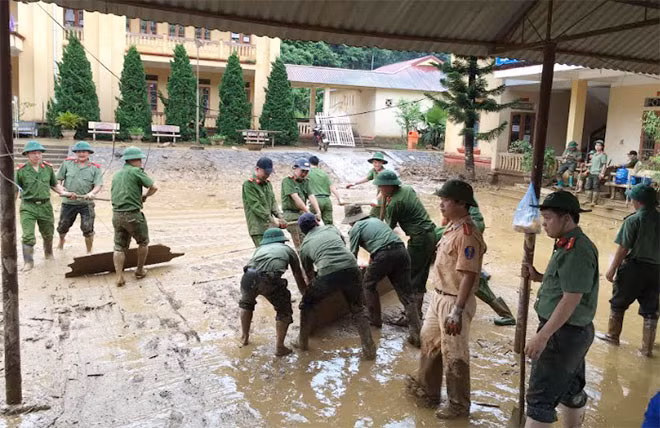 Cán bộ chiến sĩ Công an huyện Mù Cang Chải tham gia dọn bùn đất tại Trường Truung học phổ thông huyện.