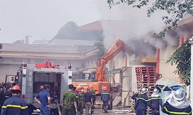 Xe máy xúc phá tường gạch để tìm cách tiếp cận đám cháy.