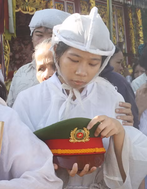 Thu Trang nâng niu chiếc mũ kê-pi của người cha anh hùng trên đường ra nghĩa trang.