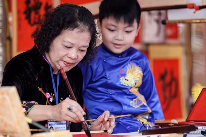 “Bà đồ” dạy chữ cho cháu bé.