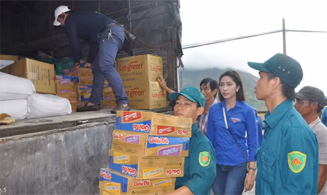 Hoa hậu 2014 Đặng Thu Thảo cùng các nhà hảo tâm và chính quyền địa phương bốc hàng cứu trợ từ trên xe tải đưa vào nơi trao quà.