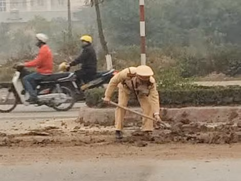 Cán bộ chiến sĩ Đội CSGT số 9 thu dọn bùn đất rơi vãi trên tuyến QL32.
