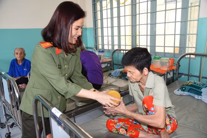 Thiếu tá Thu Quyên Phó Trưởng CQĐD-báo CAND cùng đại diện nhà tài trợ Nutifood trao sữa cho các cụ già tại Trung tâm trong sáng 30-1.