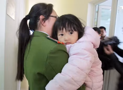 Khuôn mặt đáng yêu của cháu Hằng nép vào nữ trinh sát, còn quá nhỏ tuổi nên cháu không nhận biết được việc mình bị kẻ xấu bắt cóc.