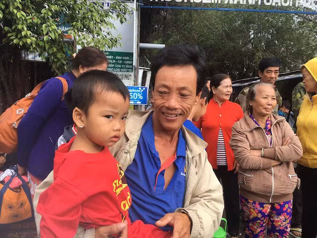 Bé gái cùng cha đi tránh bão chờ xe đến đón về nhà.