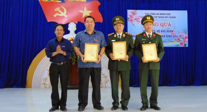 Ông Trần Duy Nghĩa, Bí thư Đảng ủy phường Điện Ngọc, trao biểu tượng ghi nhận những đóng góp trong công tác từ thiện-xã hội cho đại diện Báo CAND, Trung tướng Lê Ngọc Nam và ông Nguyễn Viết Dũng.