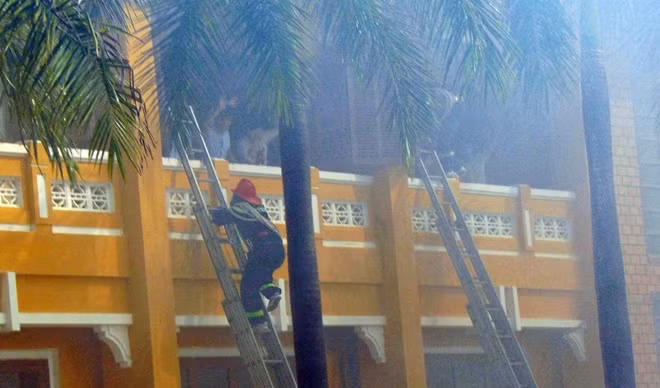 Cảnh sát PCCC&CNCH dùng thang tiếp cận tầng 2 ngôi nhà để đưa người bị mắc kẹt xuống đất an toàn.