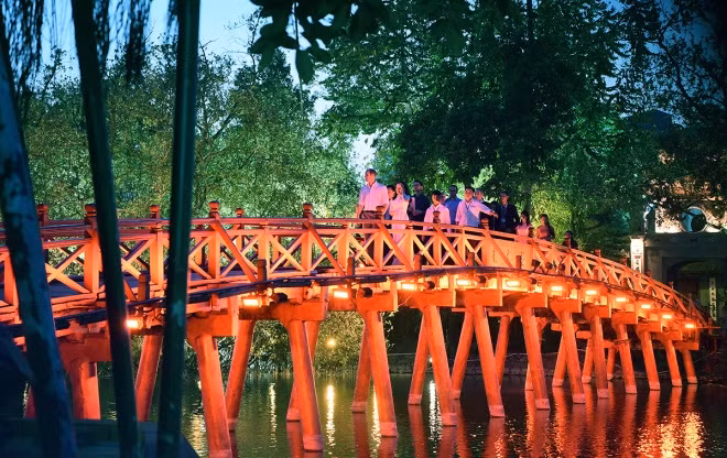Hoàng tử và đoàn tháp tùng đi bộ trên cầu Thê Húc.