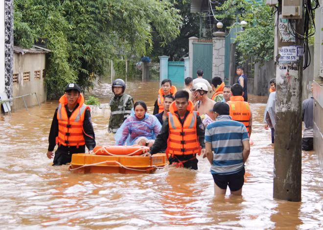 Lực lượng chức năng đưa một phụ nữ mang thai thoát khỏi vùng ngập.