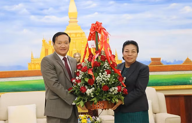 Đại sứ Việt Nam tại Lào Nguyễn Bá Hùng (trái) trao hoa chúc mừng cho Trưởng Ban Đối ngoại Trung ương Đảng nhân dân cách mạng Lào Sounthon Xayachak. (Ảnh: Xuân Tú/TTXVN)