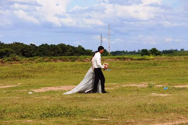 Cô dâu chú rể lãng mạn đi trên cánh đồng cừu bát ngát.