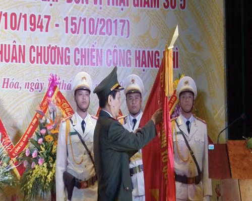 Thừa ủy quyền của Chủ tịch nước, Thứ trưởng Nguyễn Văn Sơn gắn Huân chương chiến công hạng Nhì lên lá cờ truyền thống của Trại giam số 5.