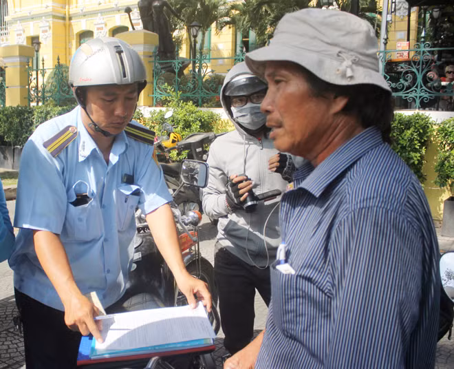 Một người bán hàng rong trước cổng Bưu điện thành phố bị TTGT lập biên bản xử lý vi phạm.