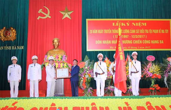 Thừa ủy quyền Chủ tịch nước, đồng chí Trương Minh Hiến, Phó chủ tịch UBND tỉnh gắn Huân chương chiến công hạng Ba lên lá cờ Truyền thống của Công an tỉnh, trao Huân chương cho Phòng CSĐTTP về ma túy Công an Hà Nam.
