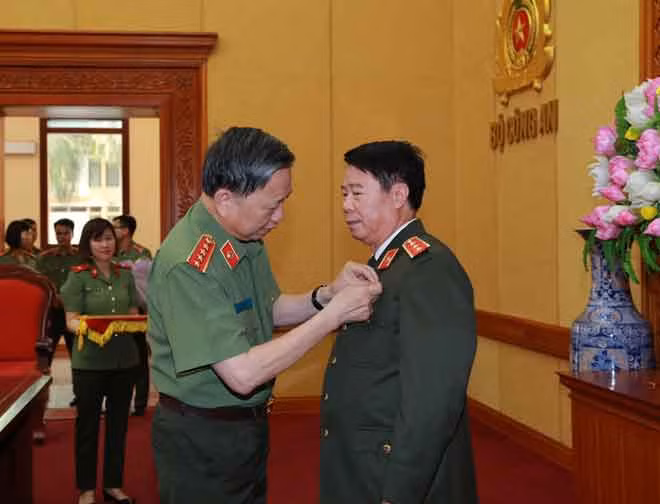 Bộ trưởng Tô Lâm trao tặng Huy hiệu 40 năm tuổi Đảng và tặng hoa chúc mừng Thứ trưởng Bùi Văn Nam.