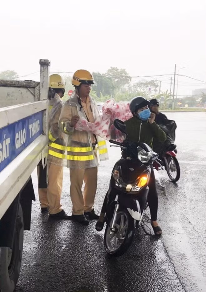 Cán bộ chiến sĩ CSGT trạm Tân Túc phát áo mưa cho người đi đường ngày 26-11.