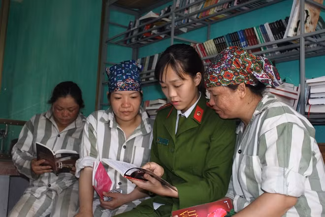 Thiếu úy Bàn Thị Huệ đọc sách tuyên truyền pháp luật cho các phạm nhân.