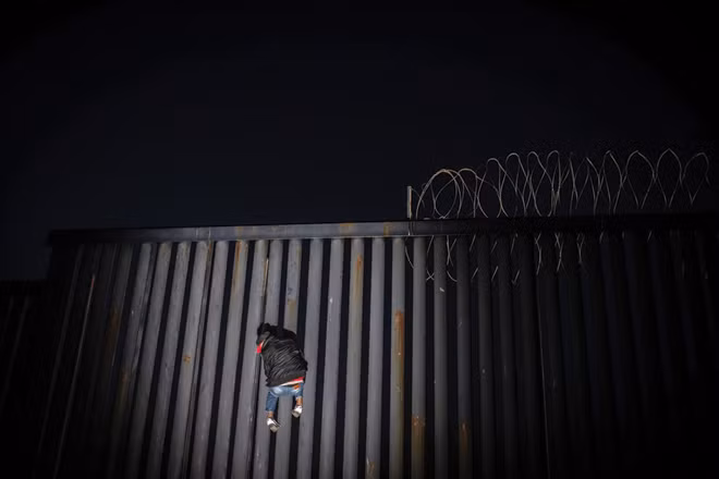 Một người đàn ông trèo lên một phần của bức tường biên giới Mỹ - Mexico ở Tijuana, Mexico, vào ngày 18-11. Tổng thống Mỹ Donald Trump muốn xây dựng một bức tường dọc theo toàn bộ biên giới phía nam để ngăn di dân vào Mỹ bất hợp pháp. Bức tường biên giới cũng là nguyên nhân chính khiến Chính phủ Mỹ đóng cửa thời gian qua. (Ảnh: Alejandro Cegarra).