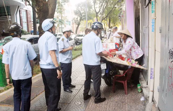 Một người bán hàng rong trước cổng Bưu điện thành phố bị TTDT lập biên bản xử lý vi phạm.