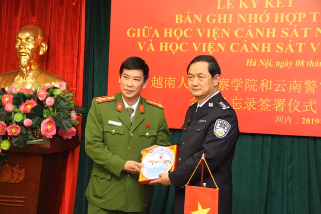 Đại tá Trần Minh Hưởng, Giám đốc Học viện CSND tặng quà lưu niệm cho đồng chí Li Gang, Bí thư Đảng ủy Học viện Cảnh sát Vân Nam.