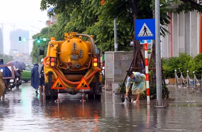 Xe hút nước, thông cống được huy động từ 7h tại đường Lê Trọng Tấn. Cả chục nhân viên thoát nước phải dùng gậy đi nhặt rác, lá cây ở các miệng cống để nước thoát.