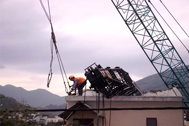 Đơn vị thi công điều động cần cẩu kéo chiếc xe cẩu bị gãy khỏi nhà dân.