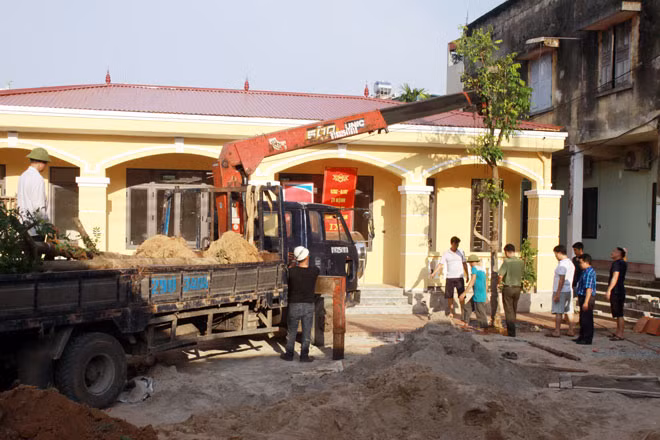 Các cán bộ Công an chính quy, công an viên bán chuyên trách và người dân xếp gạch lát sân hoàn thiện trụ sở Công an xã Kim Lũ.