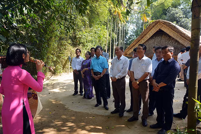 Du khách chăm chú nghe thuyết minh tại khu di tích nhà Cụ Nguyễn Sinh Sắc ở làng Sen. Ảnh: Đức Vũ