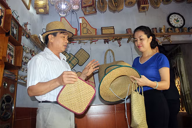 Ông Nam giới thiệu các mẫu mã sản phẩm được bện từ cỏ bàng với khách hàng.