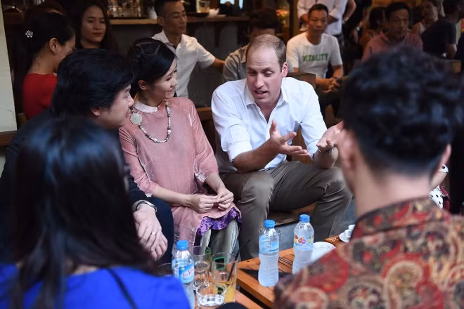 Hoàng tử William ngồi ở bộ bàn ghế kê trên vỉa hè quán cà phê, trò chuyện vui vẻ cùng các khách mời.