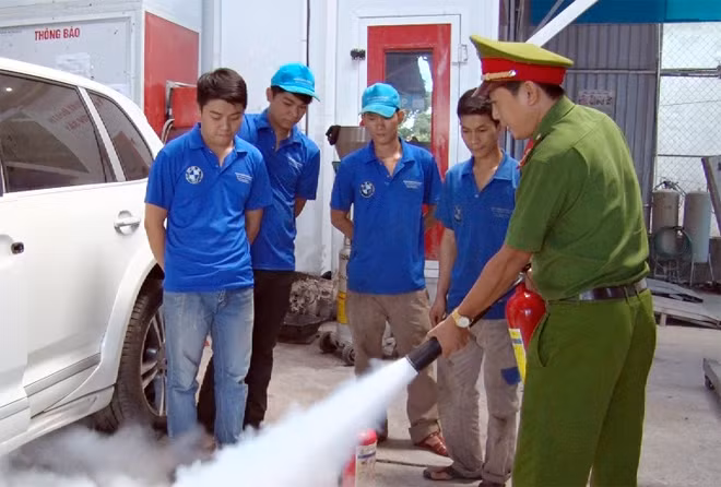 Cảnh sát PCCC hướng dẫn sử dụng bình chữa cháy cho nhân viên một gara sửa chữa ôtô.