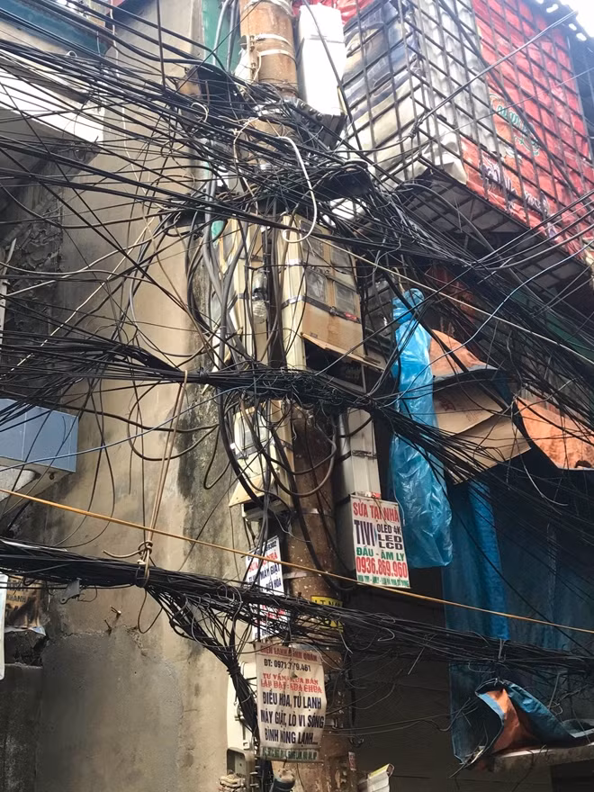 Một trong những cột điện trong ngõ phố “oằn mình” gánh hàng ngàn sợi dây điện, cáp viễn thông, luôn tiềm ẩn nguy cơ cháy nổ.