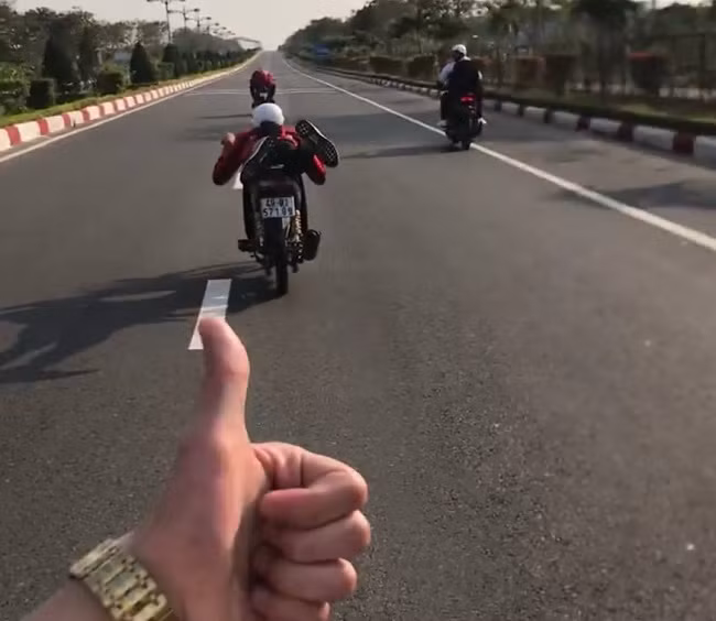 Duơng Viết Nhật Quang nằm dài trên xe cùng nhóm bạn đua trên đường cao tốc Liên Khương - Đà Lạt trước sự cổ vũ của nhiều người trong nhóm