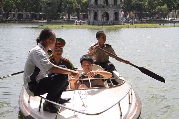 Cảnh sát trật tự Hồ Gươm cùng lực lượng bảo vệ phải dùng thuyền ra Tháp Rùa để đưa nam thanh niên này lên bờ - Ảnh: Thanh Xuân