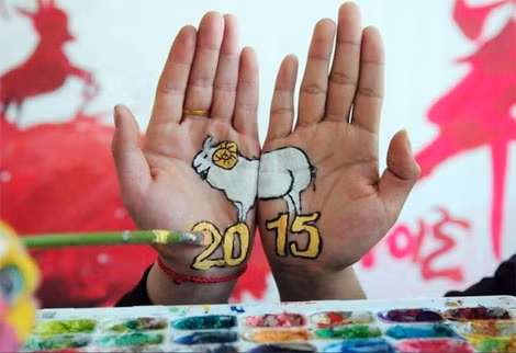Năm 2015 là năm con cừu (hoặc dê tùy quan niệm của các cộng đồng) ở Trung Quốc. Học sinh ở tỉnh Shandong vẽ trên tay biểu tượng con giáp của năm mới. Ảnh: AFP.