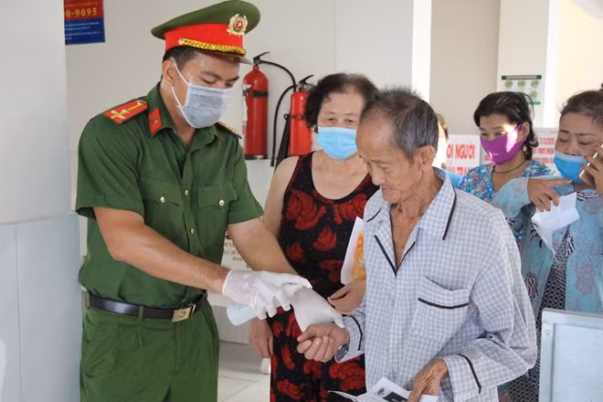 Người dân đến nhận cháo được phun nước diệt khẩn, đảm bảo công tác phòng ngừa dịch bệnh.