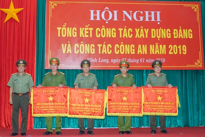 Đại tá Đoàn Minh Lý - Giám đốc Công an tỉnh Vĩnh Long trao cờ thi đua của Bộ Công an tặng các đơn vị có thành tích xuất sắc cấp cơ sở.